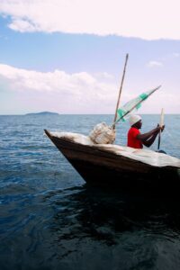 A fisherman navigates a traditional fishing boat on the calm waters of Lake Malawi, showcasing local culture.